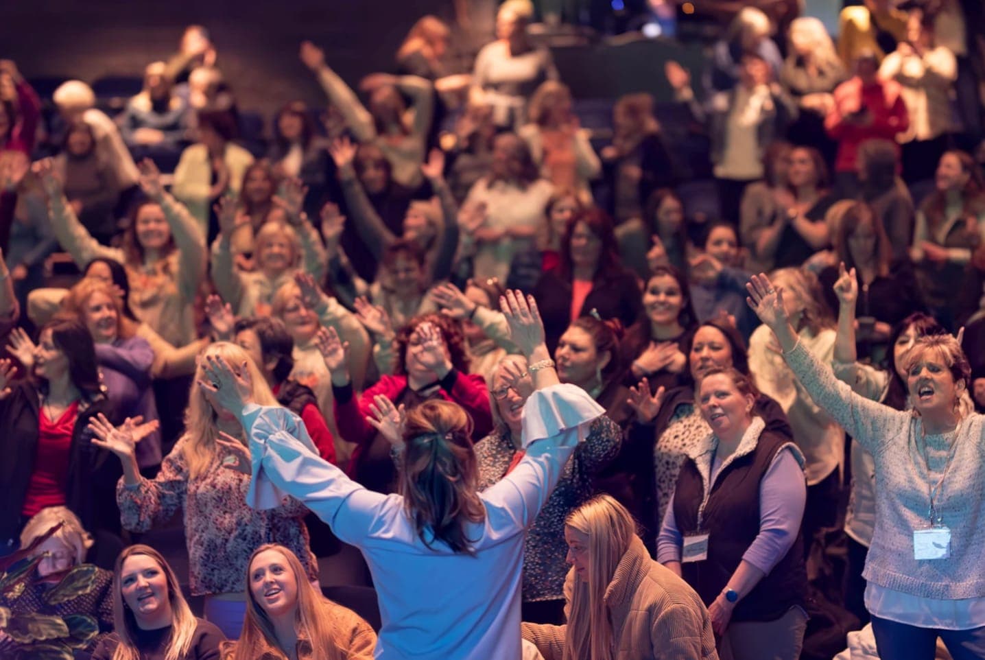 Women at InFocus Ministries event with hands raised in worship
